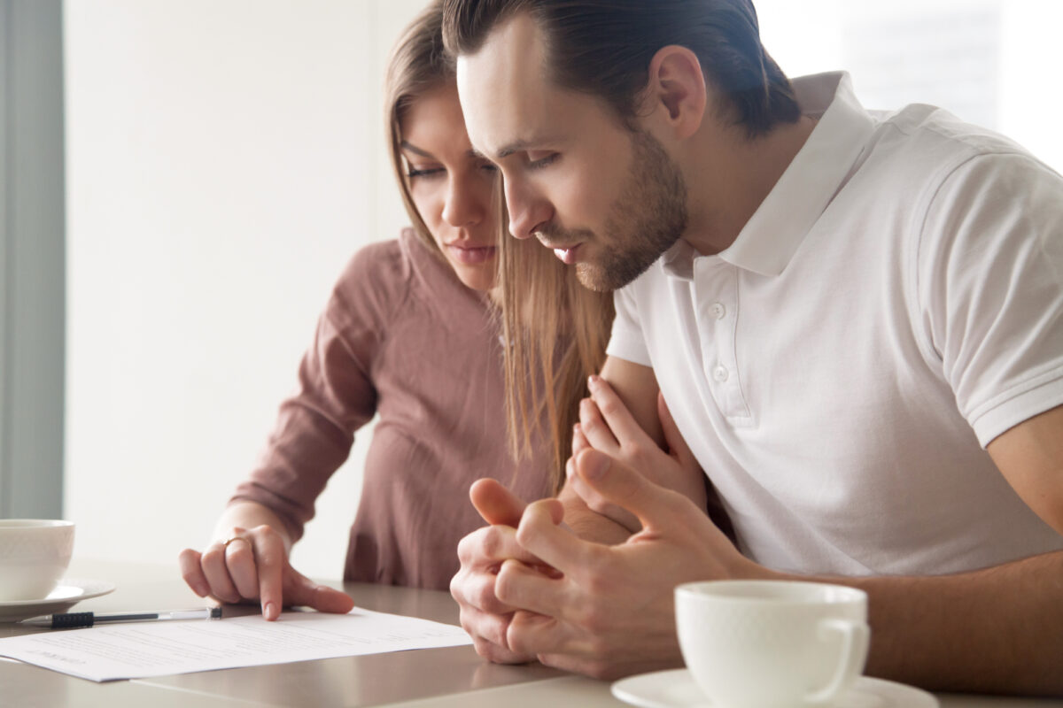 Concerned tenant reviewing lease terms and rental agreement in apartment