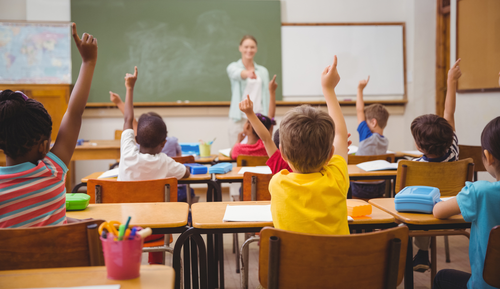 children in school raising their hands