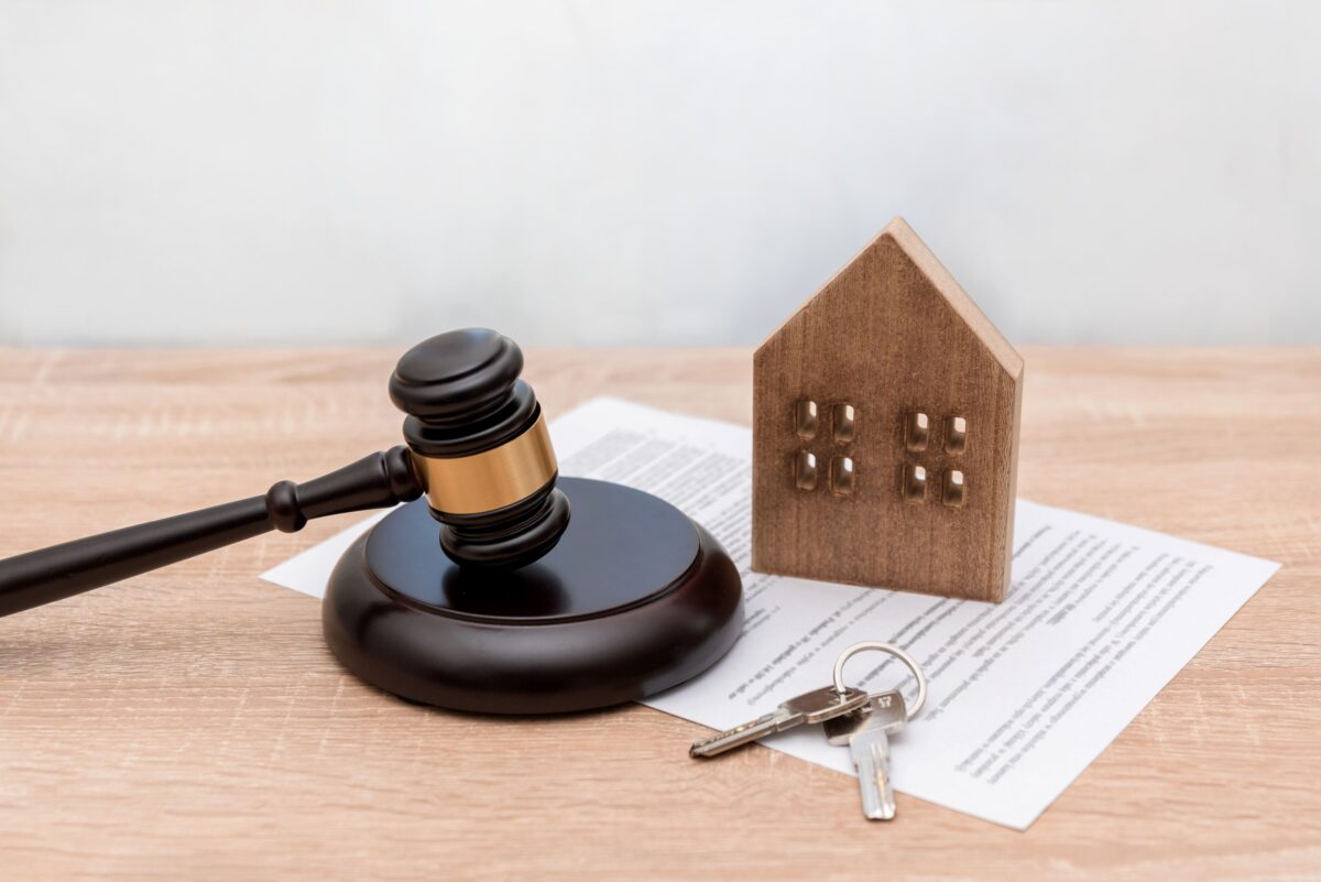 judges gavel, wooden house, keys, and real estate contract